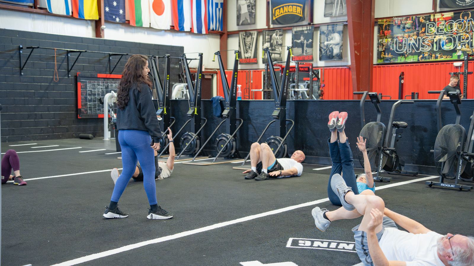 Coach walking the floor while adult members complete core work during a small-group training session